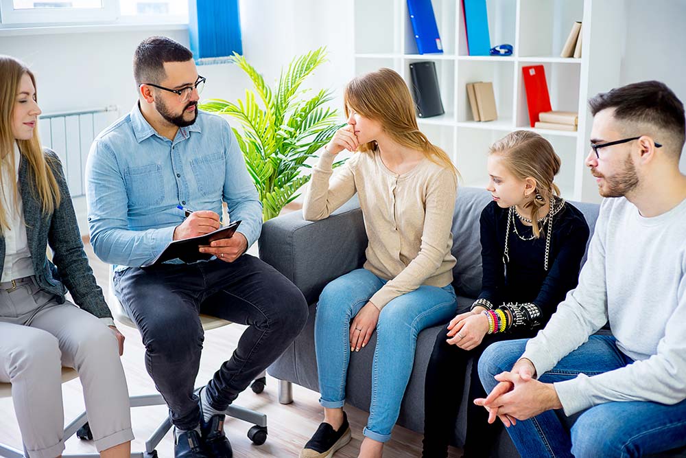 Teen girls sat on couch in discussion with Parents and Carers