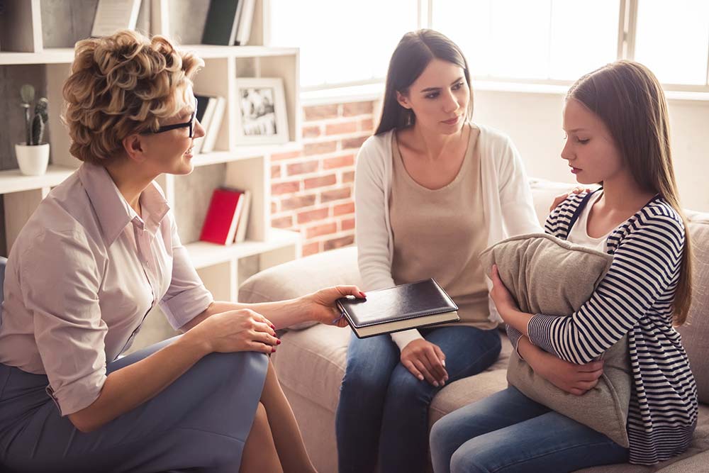 Young girl sat on couch discussing issues with carers