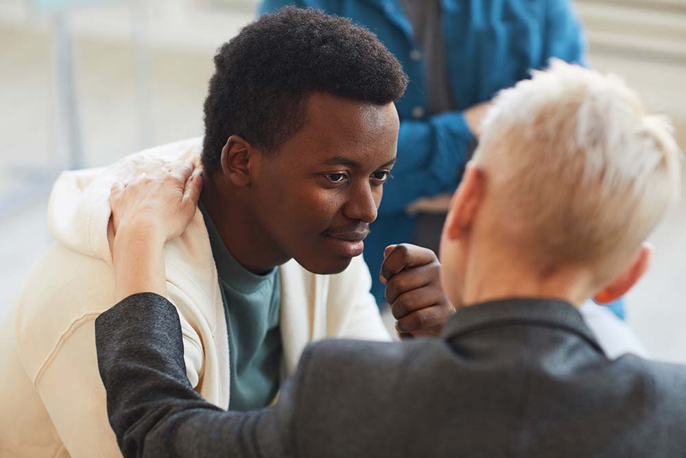 High angle view at young man smiling gratefully to carer while in support circle