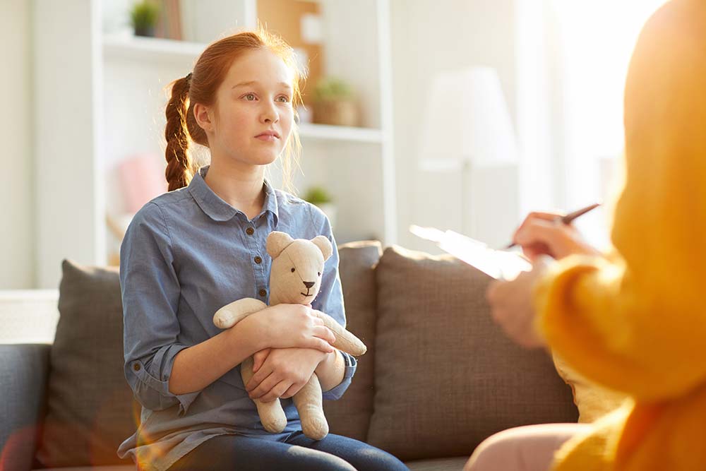 red haired teenage girl listening to counsellor during therapy session on youth issues